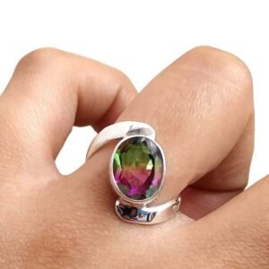 Hand wearing a silver ring with a large, oval, multi-colored gemstone