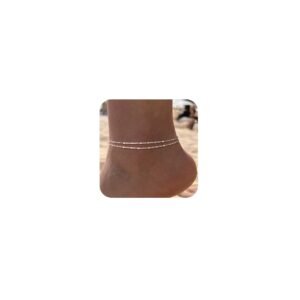 Ankle with two delicate silver anklets on a beach background