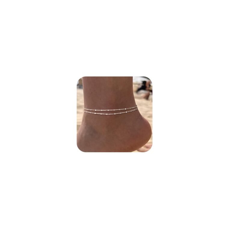 Ankle with two delicate silver anklets on a beach background