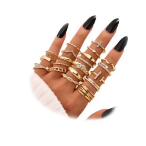 Hand wearing multiple gold rings with black nail polish on white background