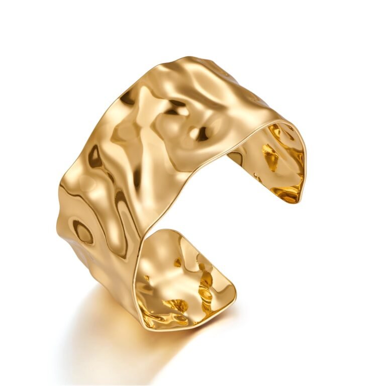 Gold-colored, textured cuff bracelet with a reflective, hammered metal finish