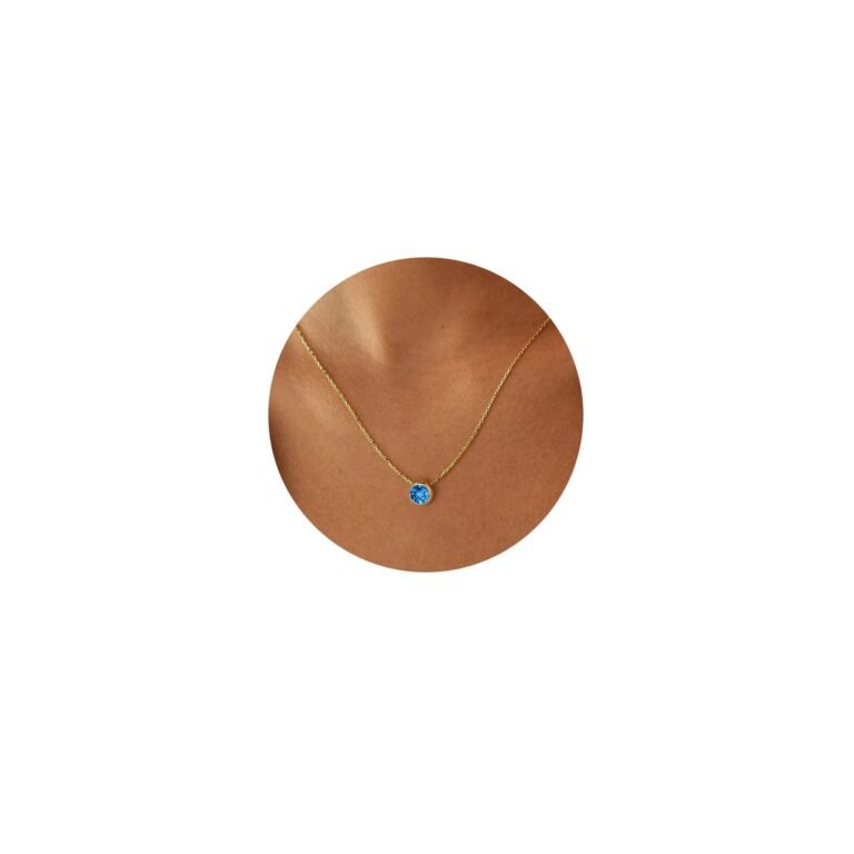 Gold necklace with a blue gemstone pendant on a person's neck
