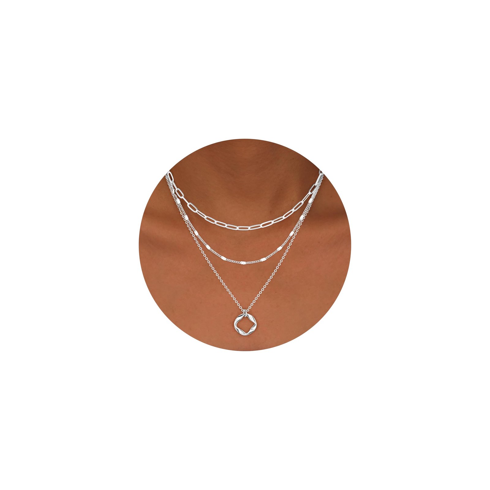 Three layered silver necklaces on a person's neck, with a pendant