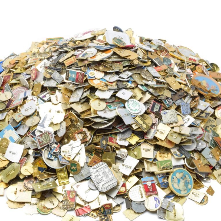Pile of assorted vintage pins and badges, many with Cyrillic text, on white background